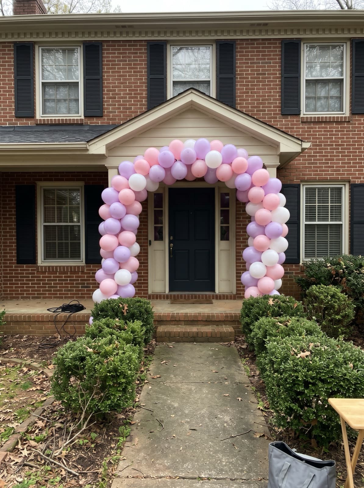 Pastel balloon arch over the front door of a brick house