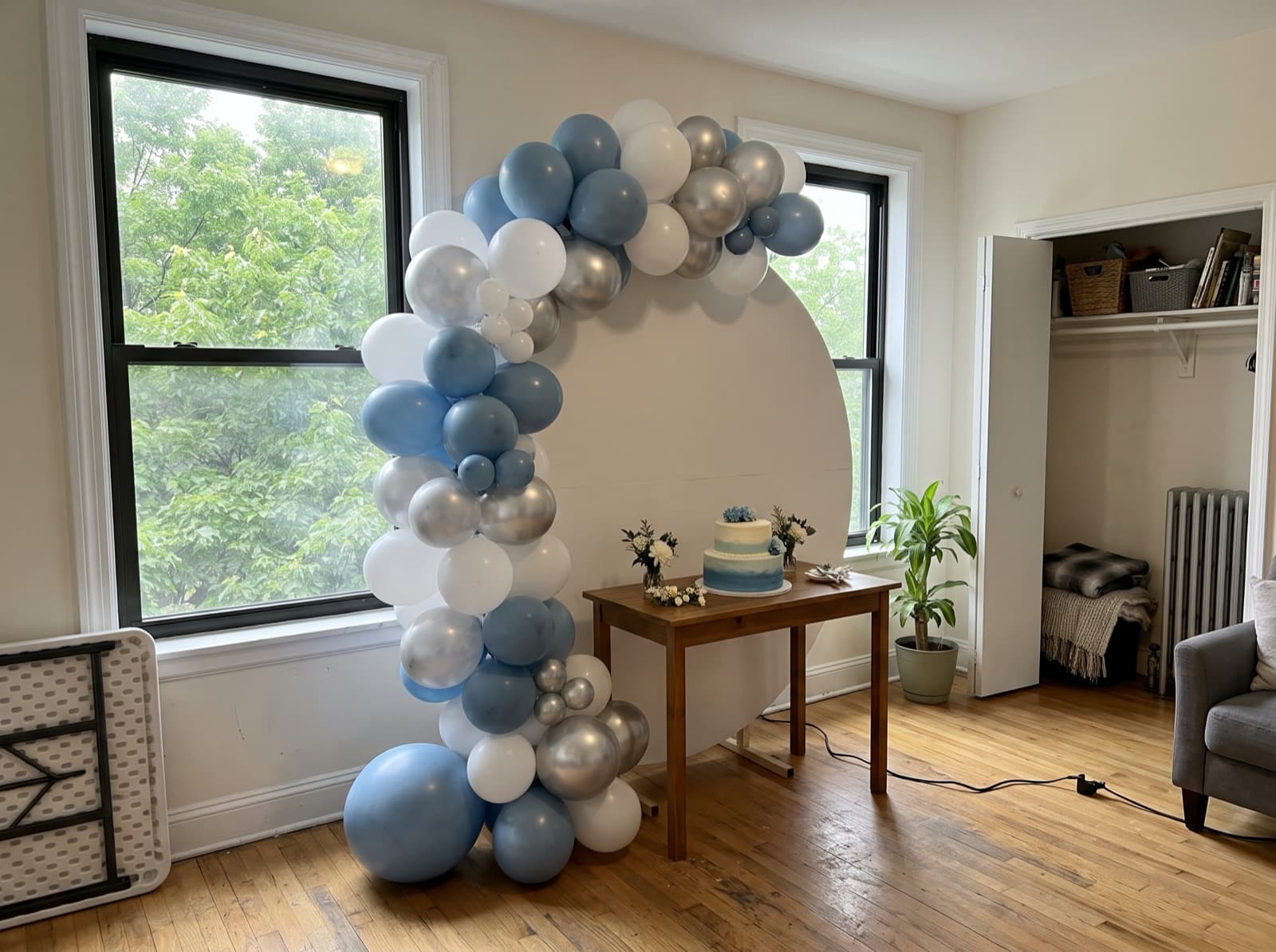 Half balloon arch curving over a cake table in an apartment